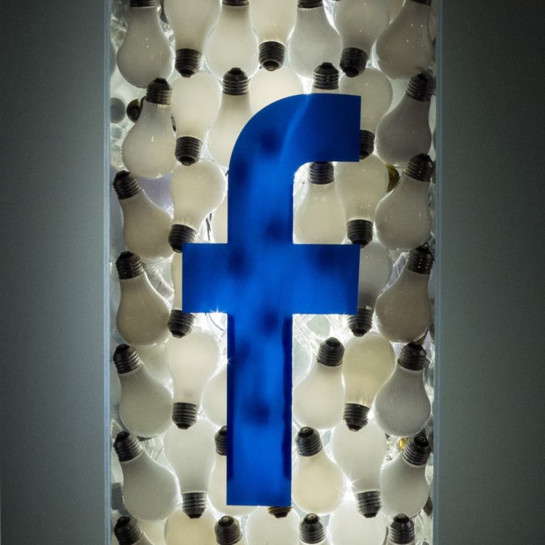 Das Facebook-Logo in einer Röhre mit Glühbirnen.
