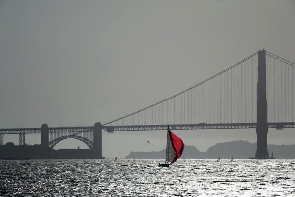 a colorful sailboat in front of the Golden Gate Bridge