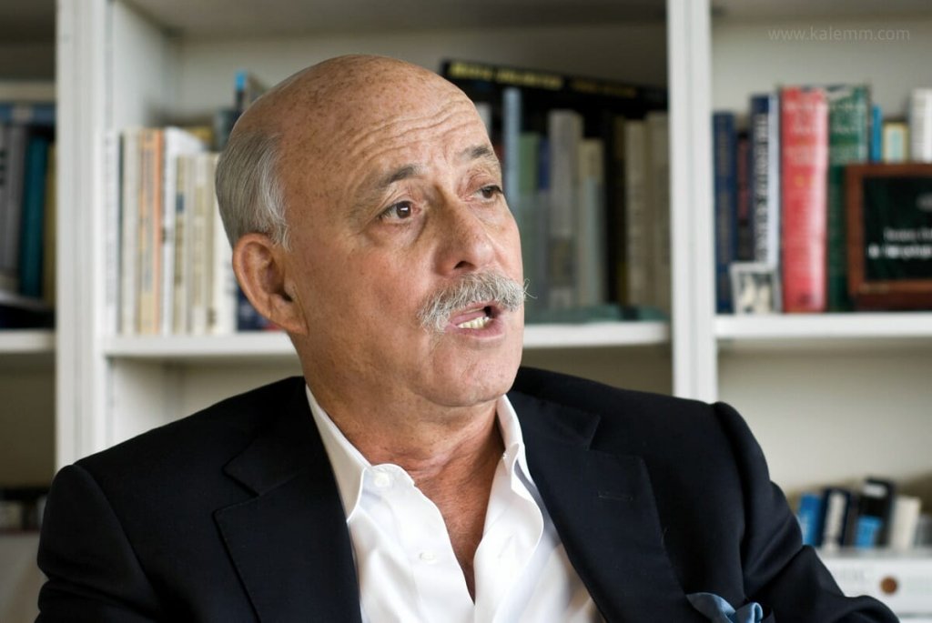 Portrait of bestselling author and consultant Jeremy Rifkin, seen at his office, speaking, in front of shelves full of books.