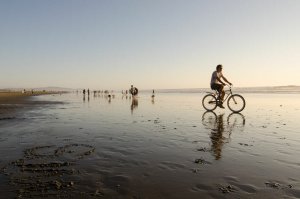 a bike rider and pedestrians enjoying a calm day on Ocean Beach in San Francisco